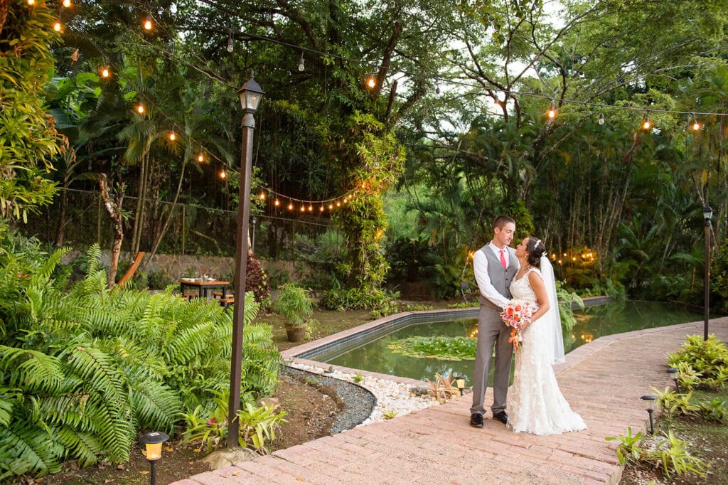 Elegant Puerto Rico wedding photographer capturing romantic couple in lush garden setting with string lights.