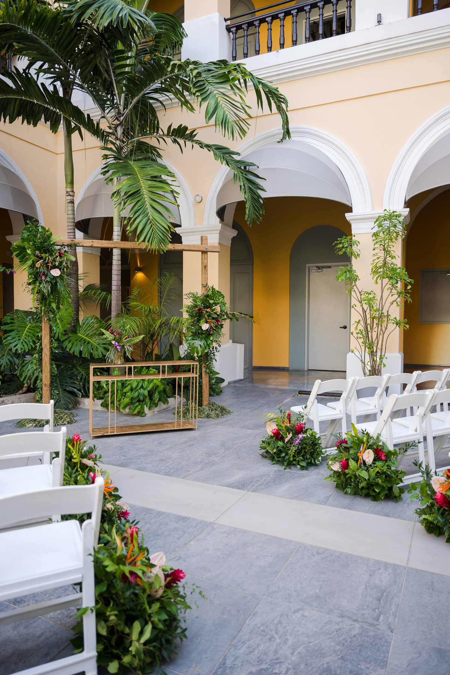 Elegant ceremony setup with tropical floral arrangements and wooden arch at an intimate destination wedding venue in Old San Juan.