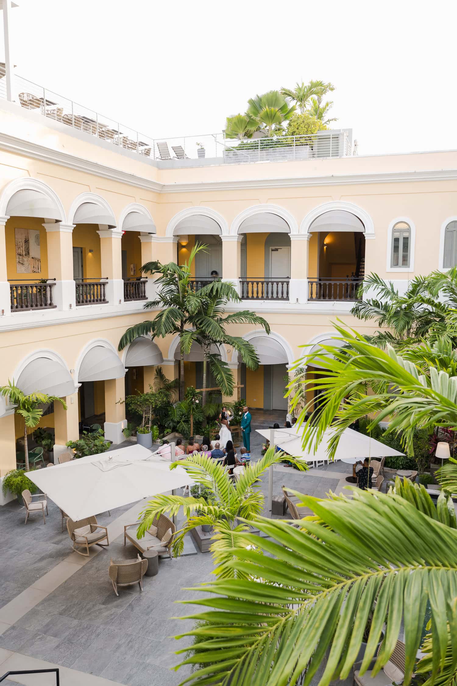 Aerial view of a courtyard ceremony in Palacio Provincial surrounded by lush greenery at a historic venue during an intimate destination wedding in Old San Juan.