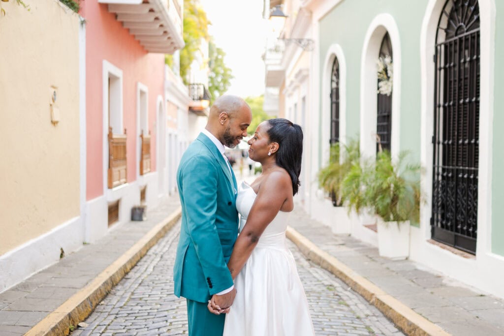 Couple standing in front of a colorful wall on a cobblestone street during their intimate destination wedding photoshoot in Old San Juan.