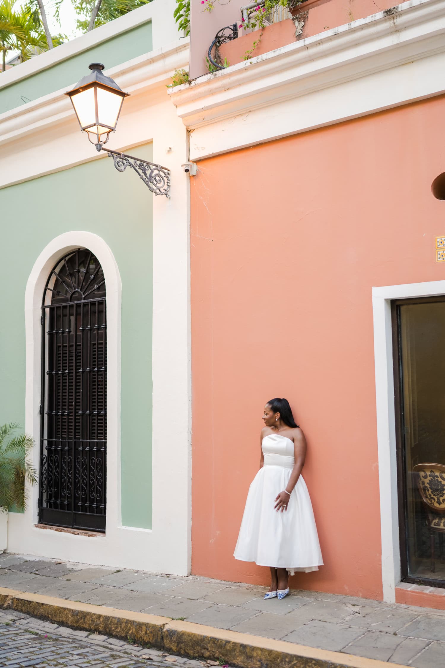 Bride standing against a colorful wall on a cobblestone street during her intimate destination wedding photoshoot in Old San Juan.