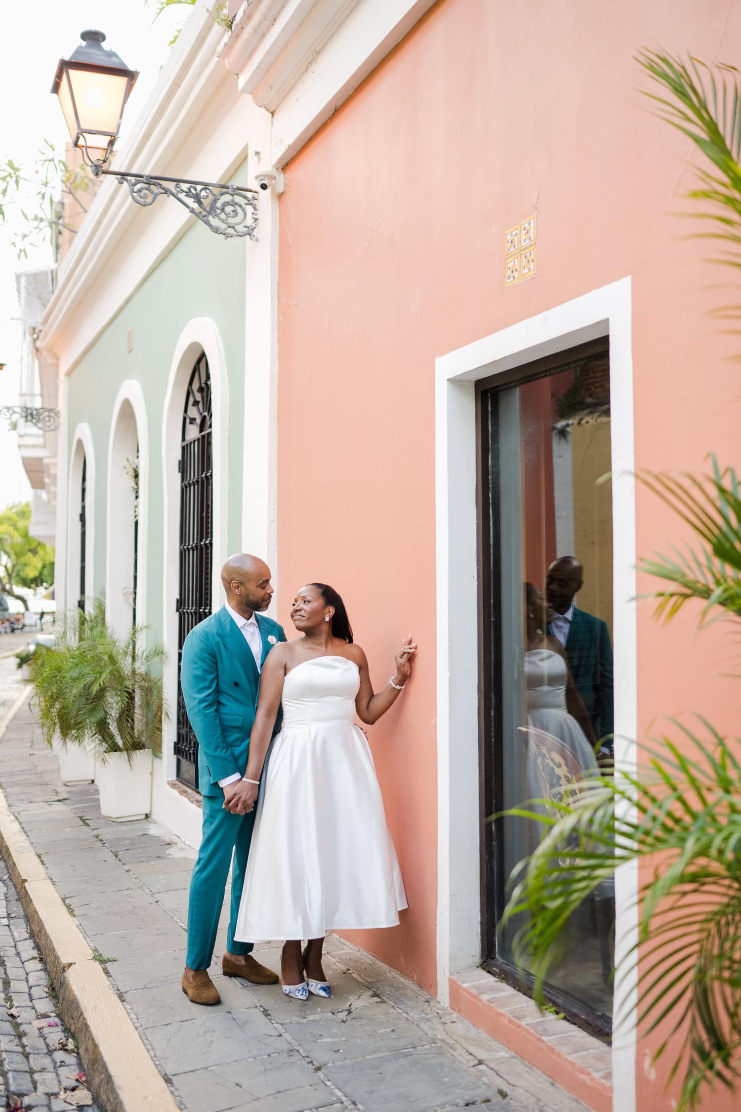 Couple standing in front of a colorful wall on a cobblestone street during their intimate destination wedding photoshoot in Old San Juan.