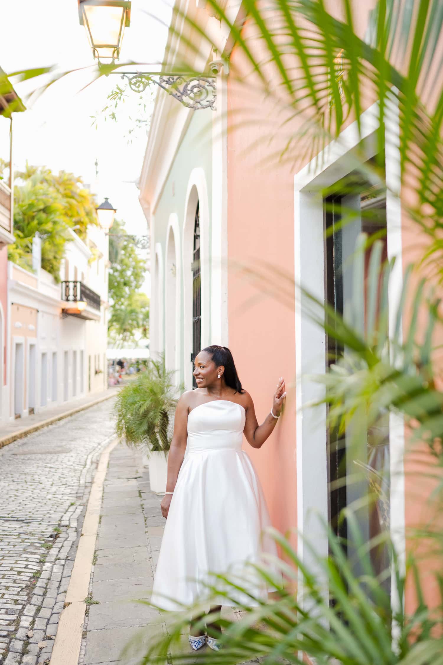 Bride standing against a colorful wall on a cobblestone street during her intimate destination wedding photoshoot in Old San Juan.