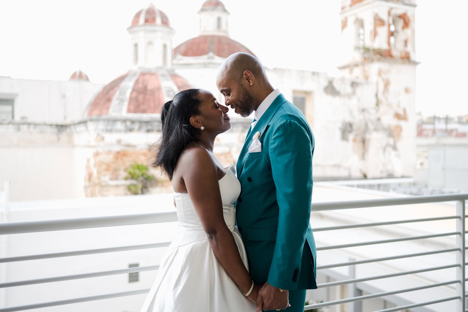 A newlywed couple sharing a tender moment on a rooftop with historic Old San Juan architecture in the background during their intimate destination wedding.