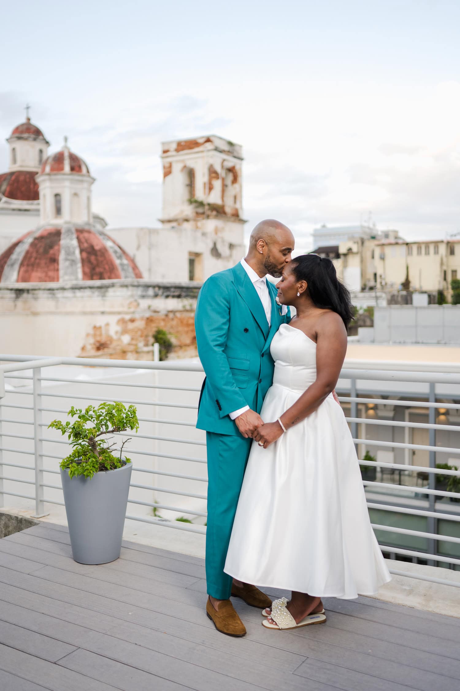 A newlywed couple sharing a tender moment on a rooftop with historic Old San Juan architecture in the background during their intimate destination wedding.