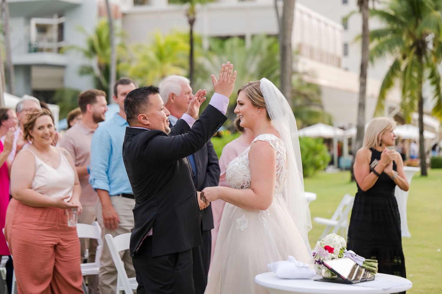 Beachfront wedding ceremony setup with a floral arch and palm trees at Courtyard Marriott Isla Verde, Puerto Rico.