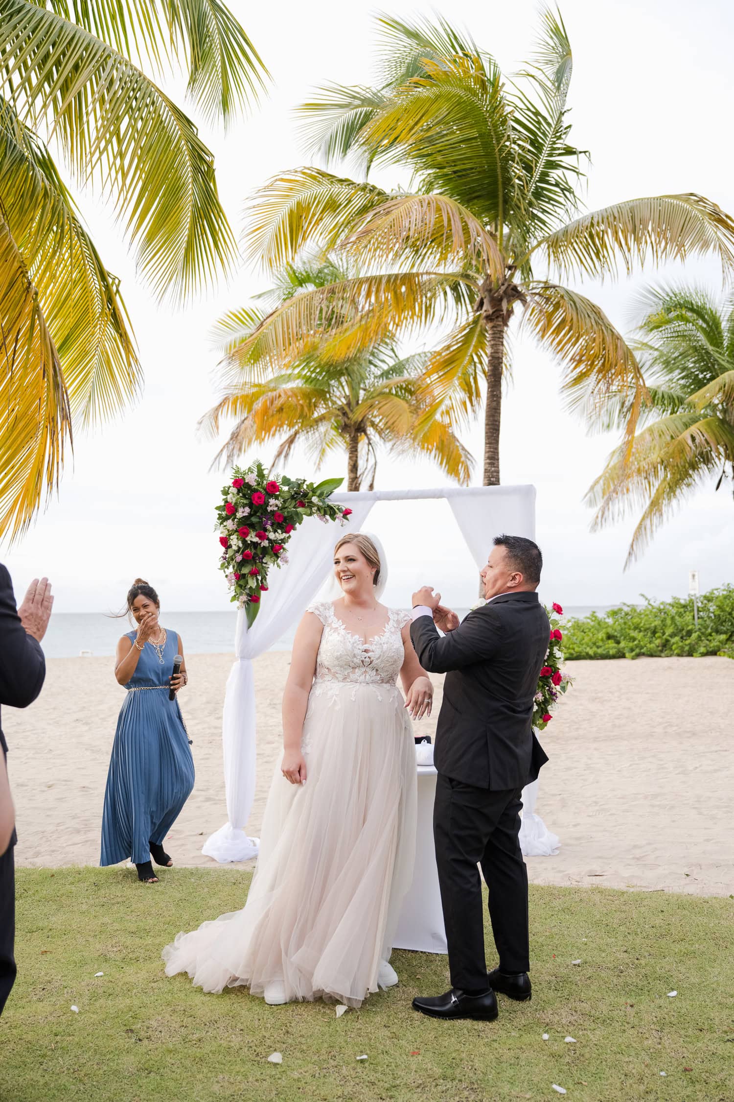 Beachfront wedding ceremony setup with a floral arch and palm trees at Courtyard Marriott Isla Verde, Puerto Rico.