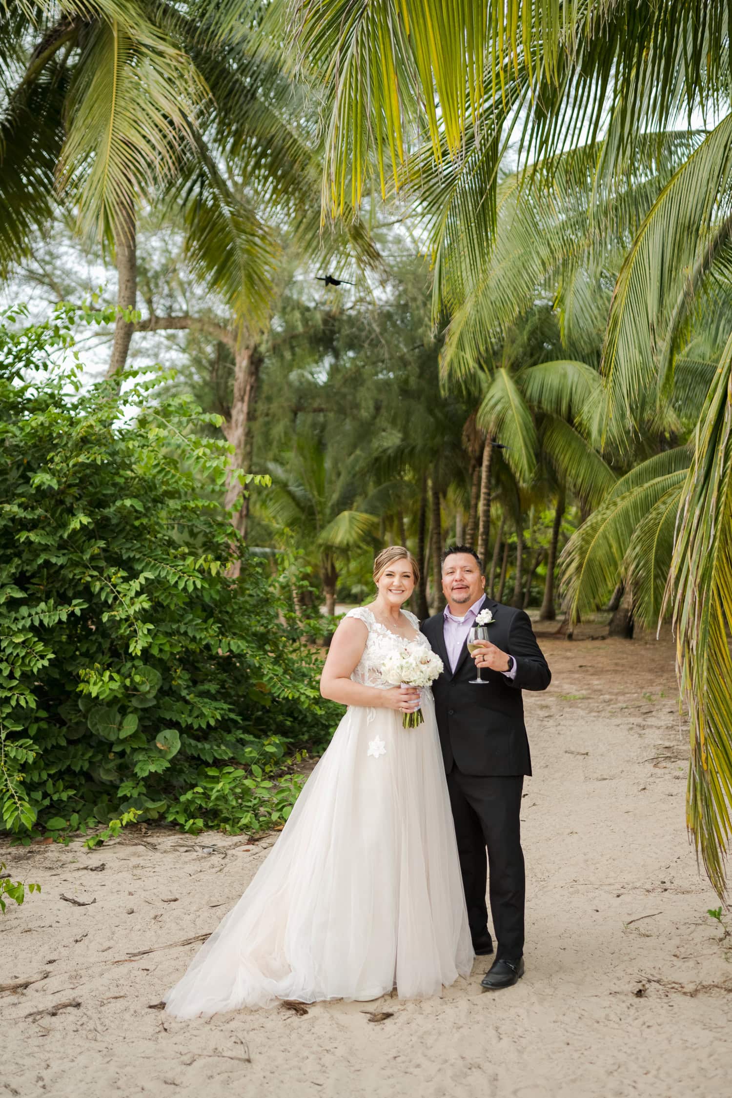 Beachfront wedding ceremony setup with a floral arch and palm trees at Courtyard Marriott Isla Verde, Puerto Rico.