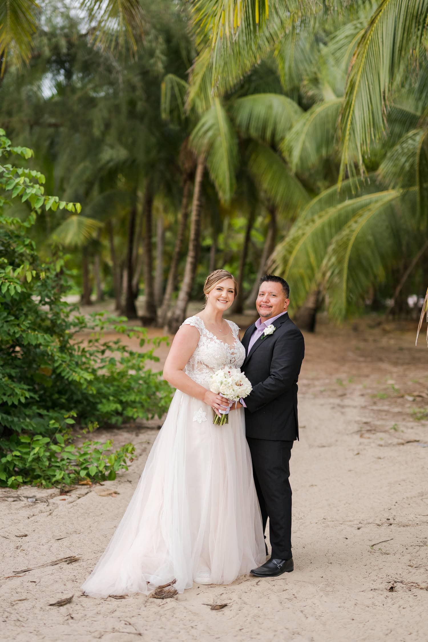 Beachfront wedding ceremony setup with a floral arch and palm trees at Courtyard Marriott Isla Verde, Puerto Rico.