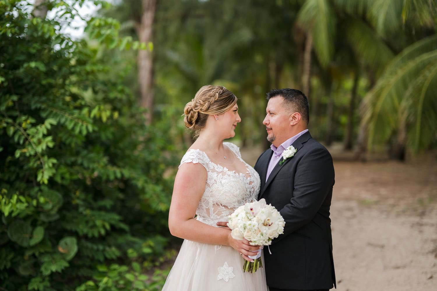 Beachfront wedding ceremony setup with a floral arch and palm trees at Courtyard Marriott Isla Verde, Puerto Rico.