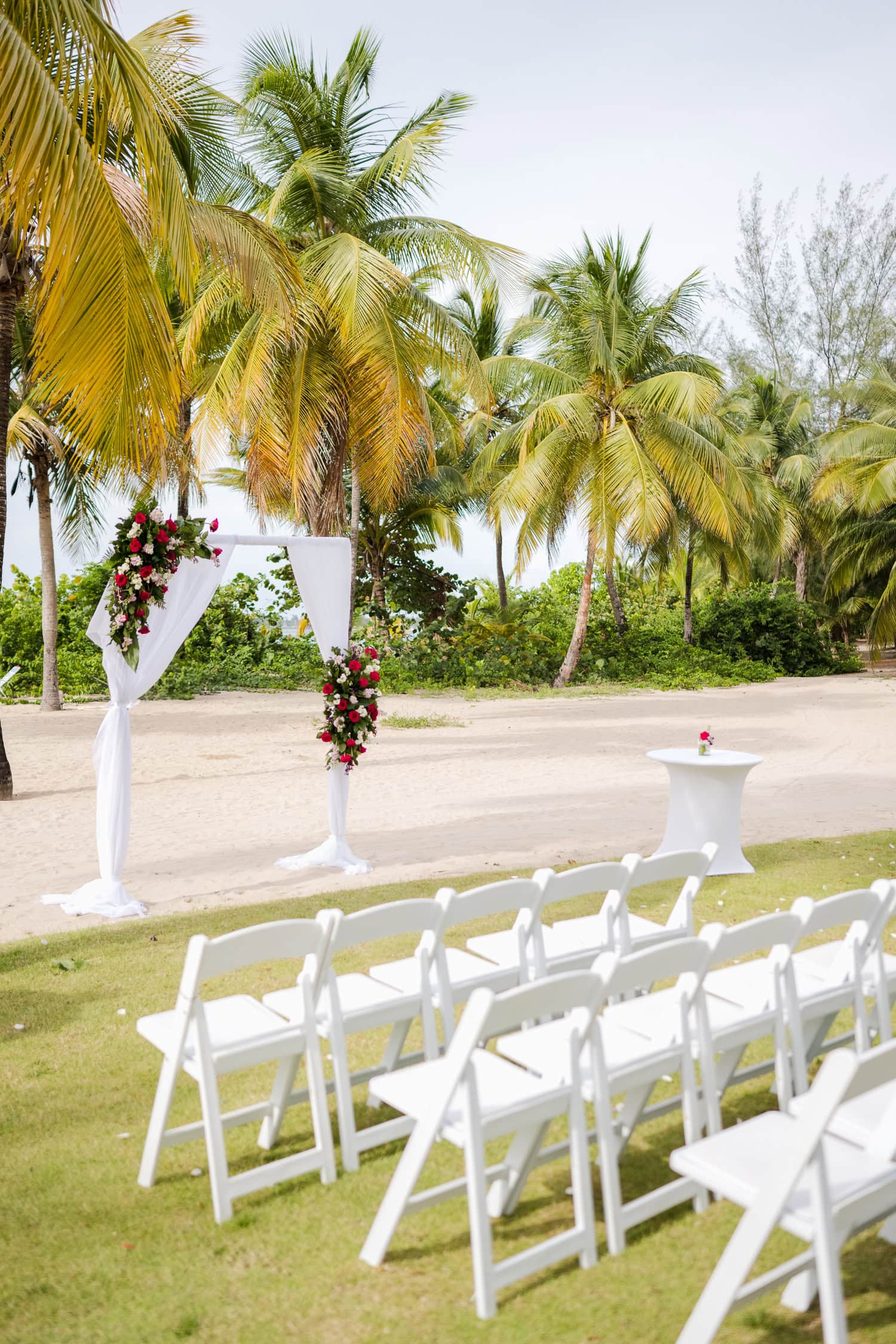 Beachfront wedding ceremony setup with a floral arch and palm trees at Courtyard Marriott Isla Verde, Puerto Rico.