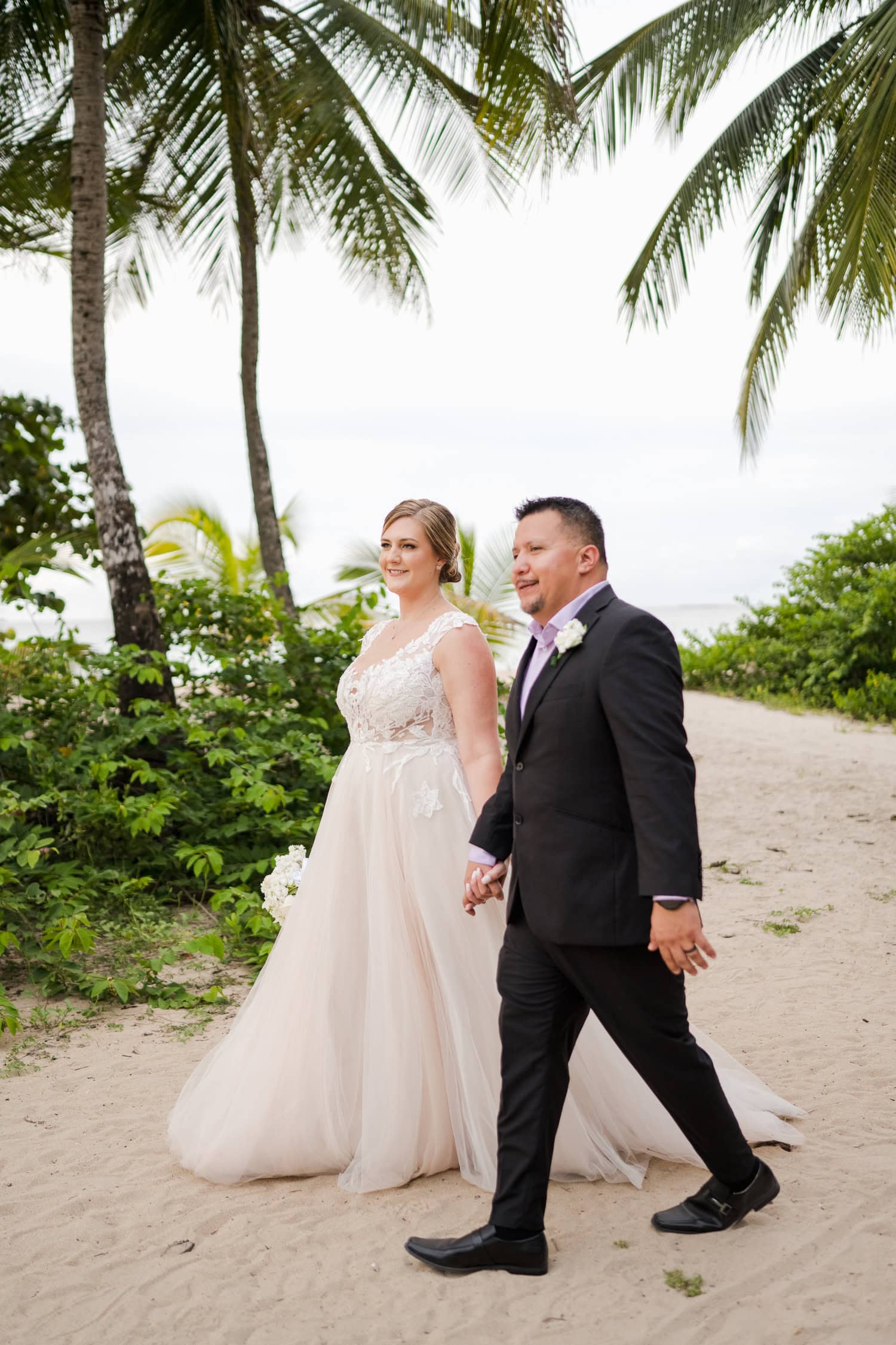 Beachfront wedding ceremony setup with a floral arch and palm trees at Courtyard Marriott Isla Verde, Puerto Rico.