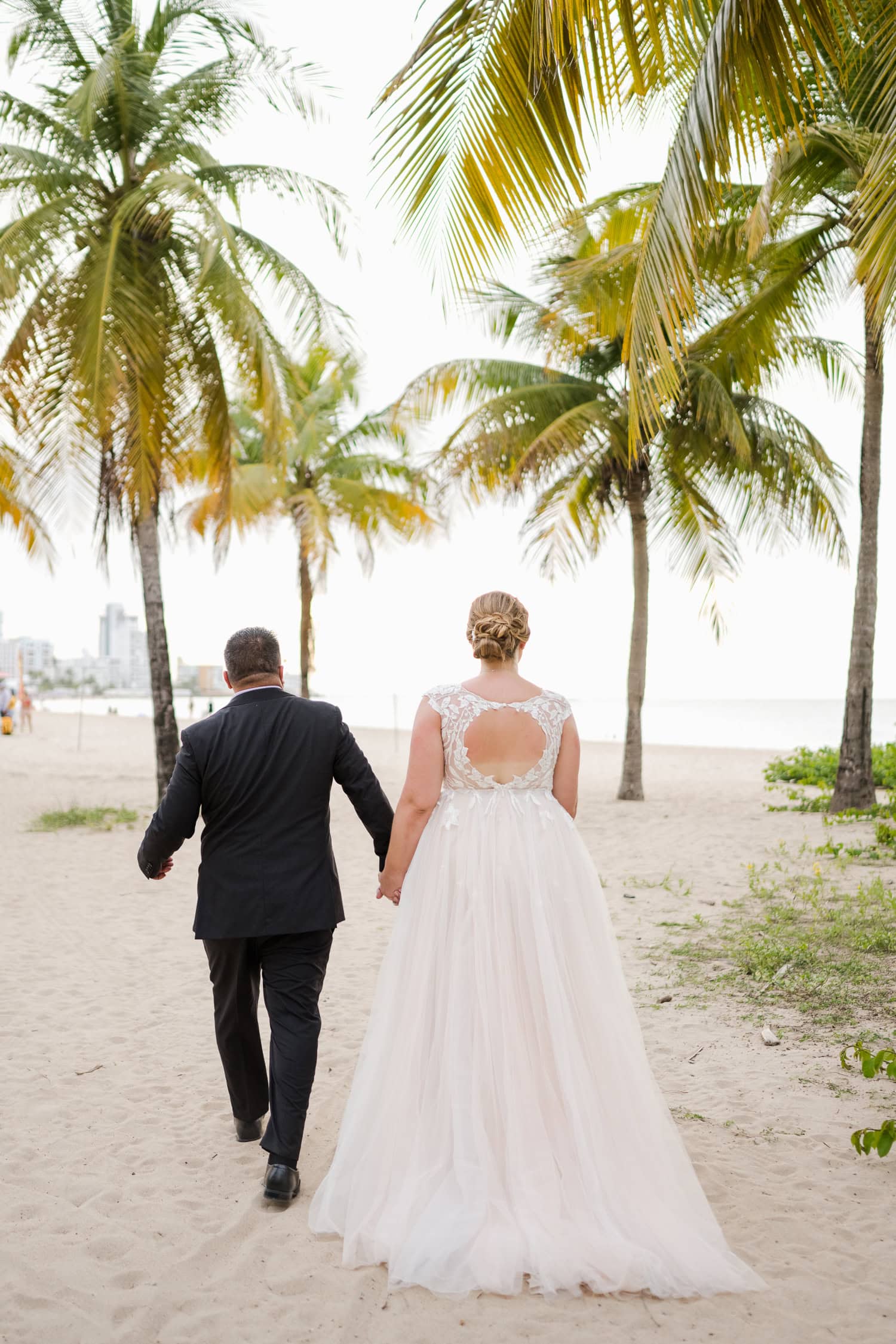 Beachfront wedding ceremony setup with a floral arch and palm trees at Courtyard Marriott Isla Verde, Puerto Rico.