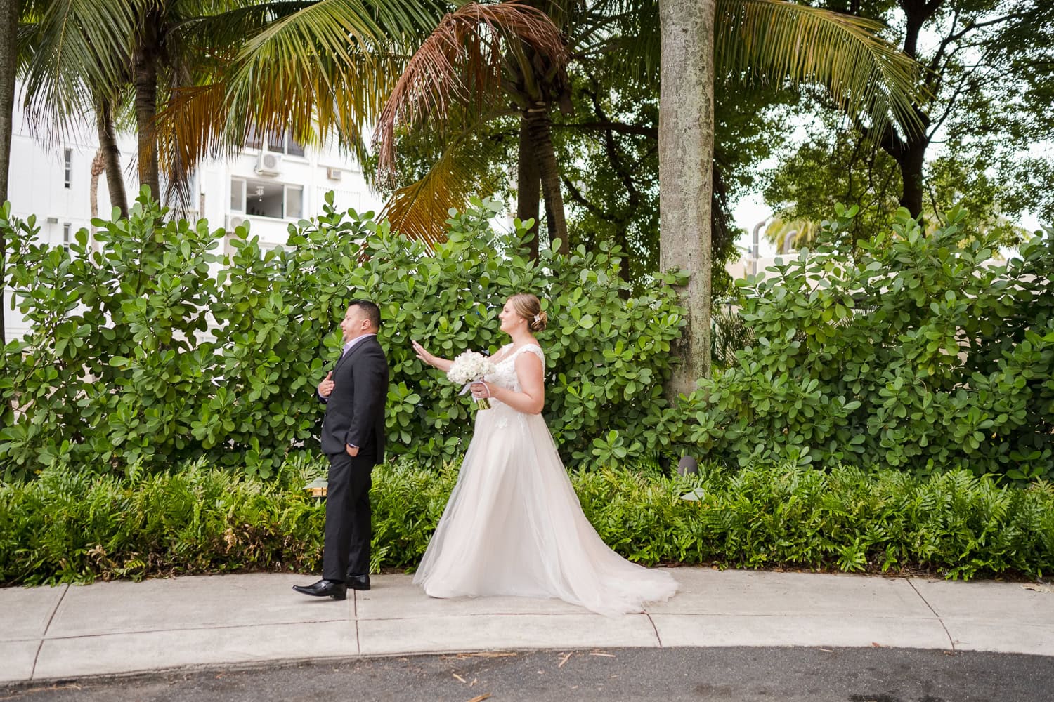 Beachfront wedding ceremony setup with a floral arch and palm trees at Courtyard Marriott Isla Verde, Puerto Rico.