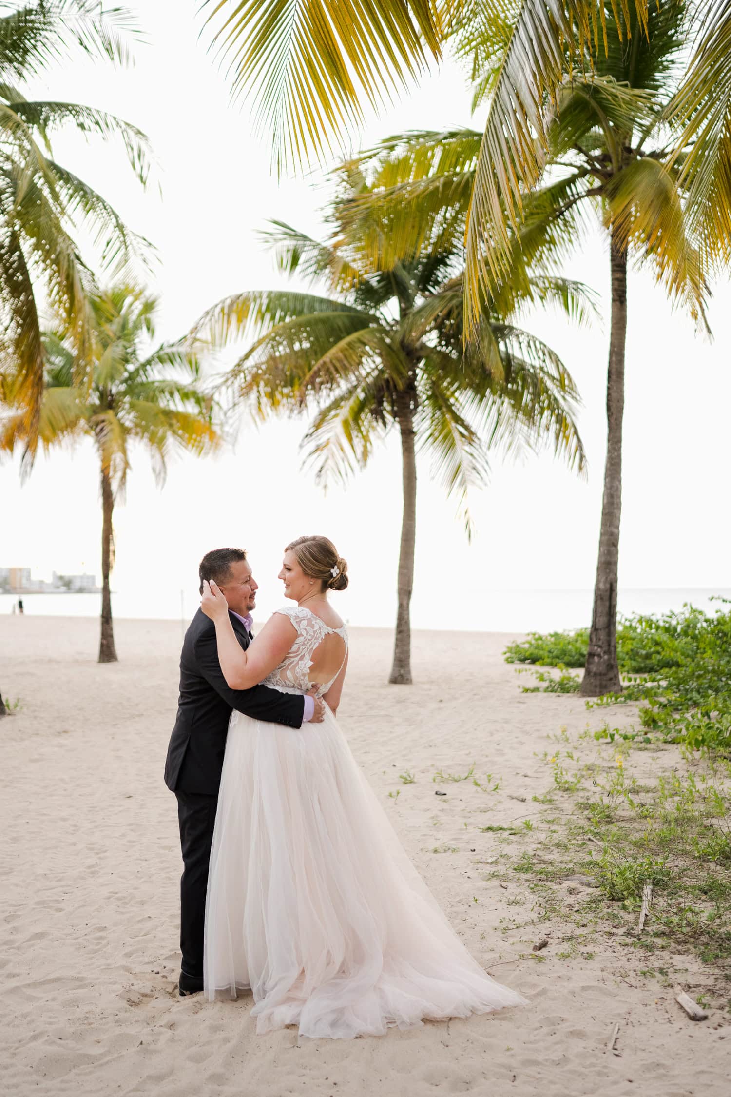 Beachfront wedding ceremony setup with a floral arch and palm trees at Courtyard Marriott Isla Verde, Puerto Rico.