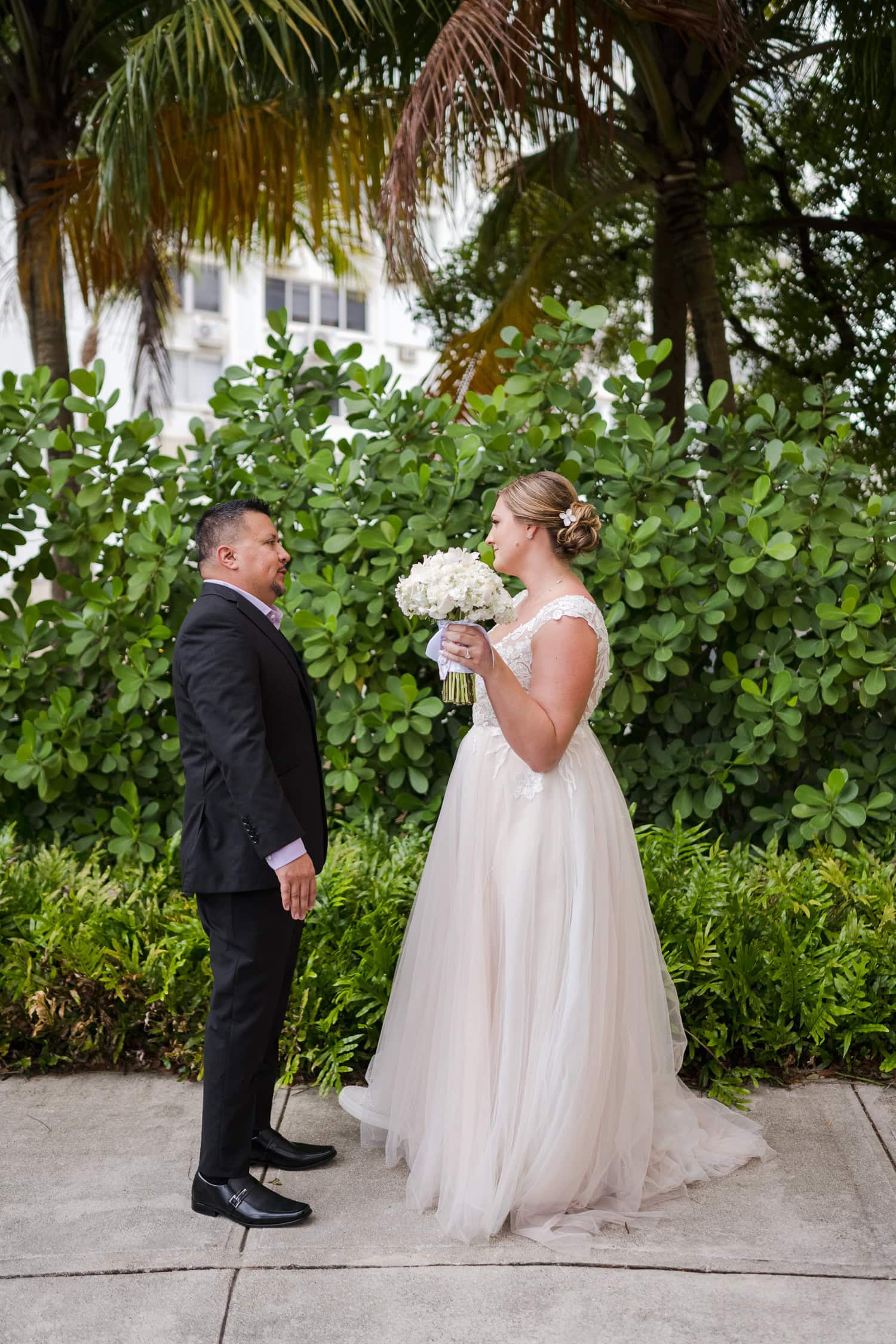 Beachfront wedding ceremony setup with a floral arch and palm trees at Courtyard Marriott Isla Verde, Puerto Rico.