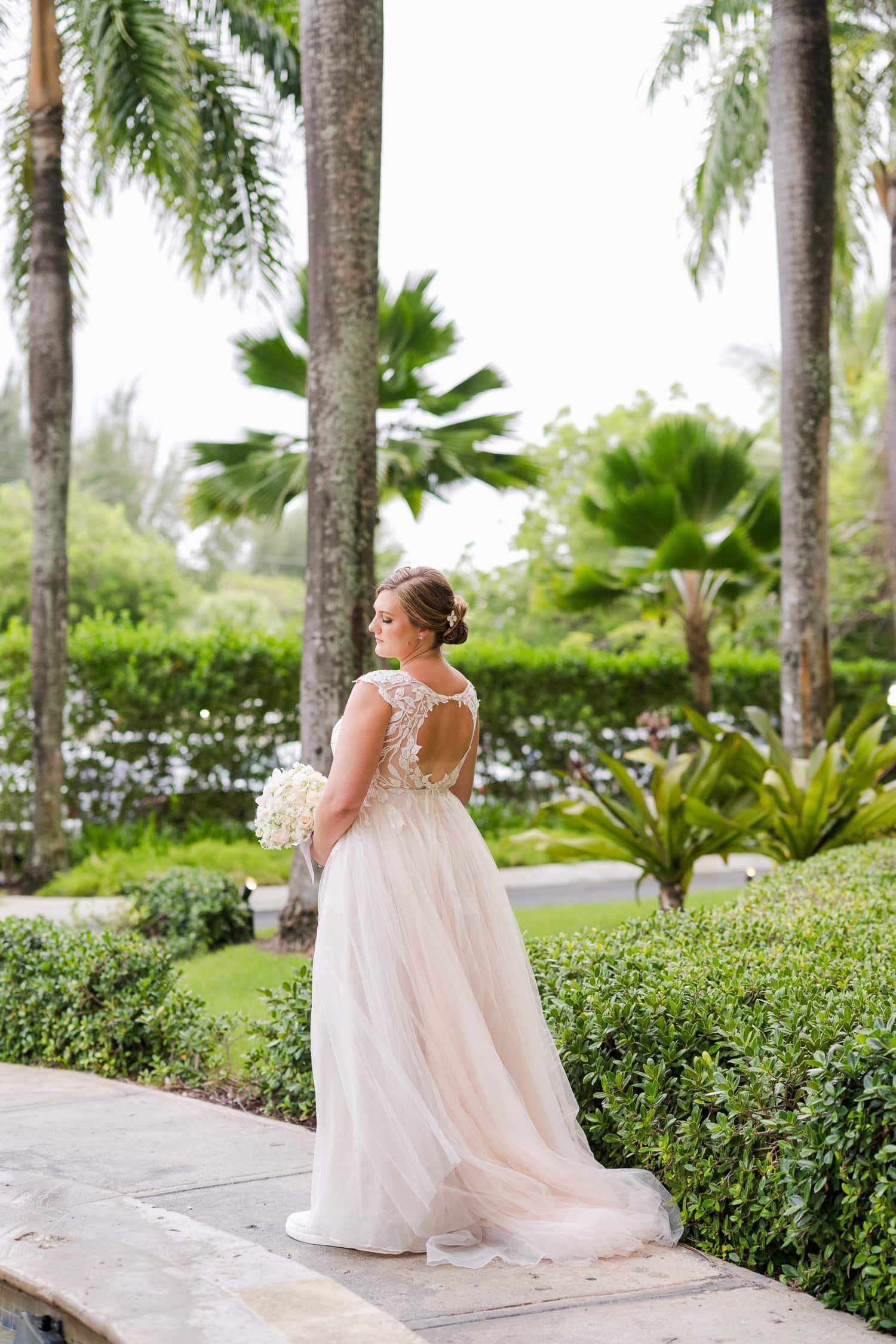 Beachfront wedding ceremony setup with a floral arch and palm trees at Courtyard Marriott Isla Verde, Puerto Rico.