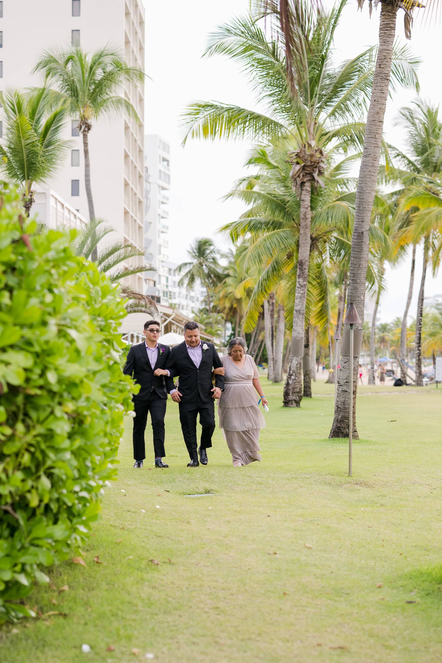 Beachfront wedding ceremony setup with a floral arch and palm trees at Courtyard Marriott Isla Verde, Puerto Rico.