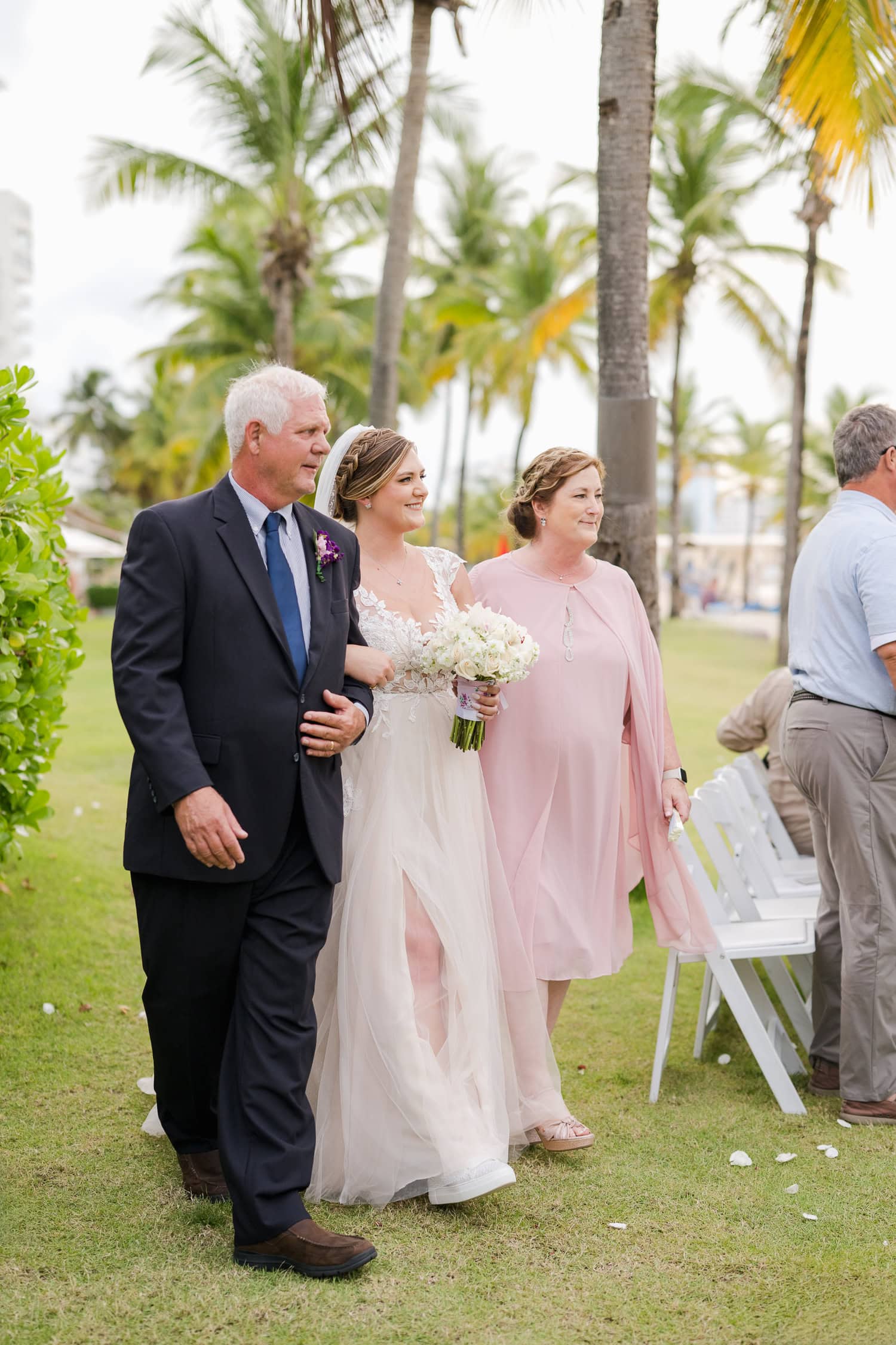 Beachfront wedding ceremony setup with a floral arch and palm trees at Courtyard Marriott Isla Verde, Puerto Rico.