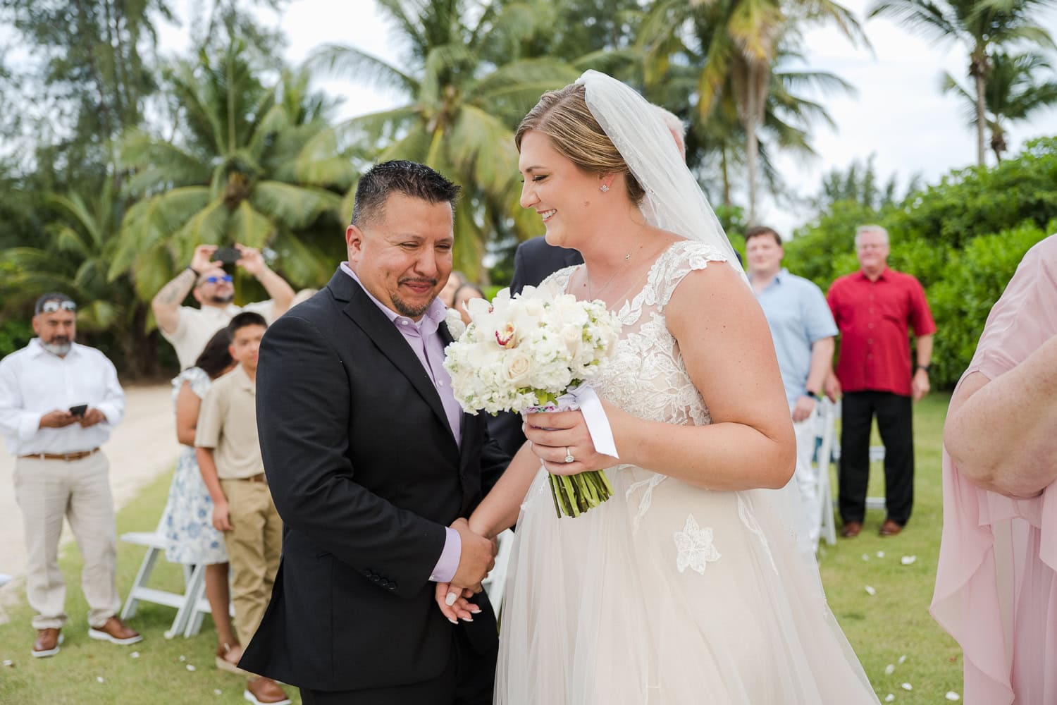 Beachfront wedding ceremony setup with a floral arch and palm trees at Courtyard Marriott Isla Verde, Puerto Rico.