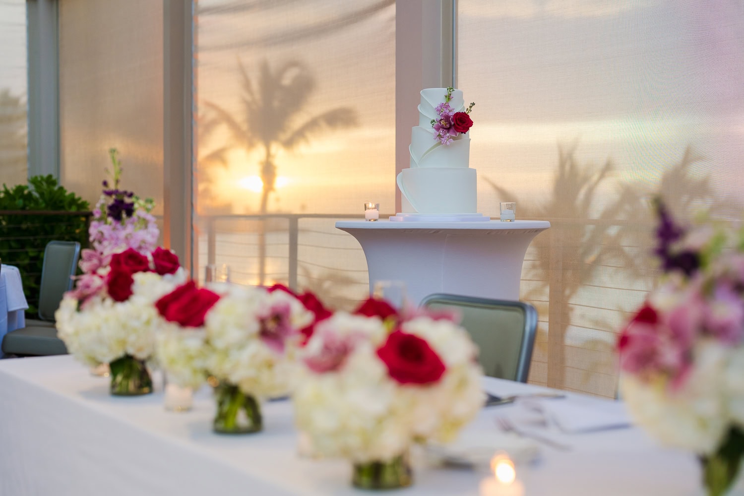 Beachfront wedding ceremony setup with a floral arch and palm trees at Courtyard Marriott Isla Verde, Puerto Rico.