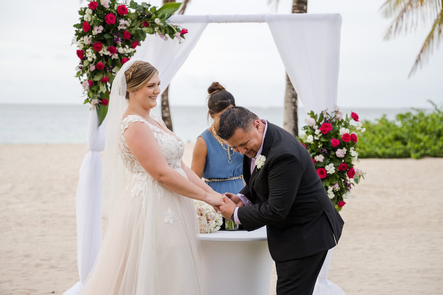 Beachfront wedding ceremony setup with a floral arch and palm trees at Courtyard Marriott Isla Verde, Puerto Rico.