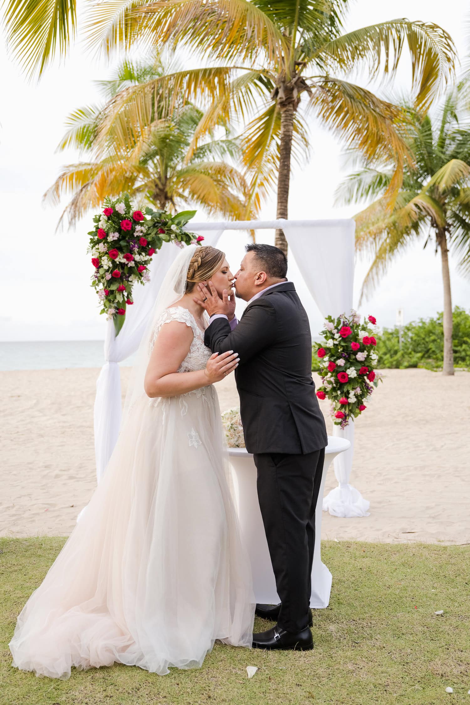 Beachfront wedding ceremony setup with a floral arch and palm trees at Courtyard Marriott Isla Verde, Puerto Rico.