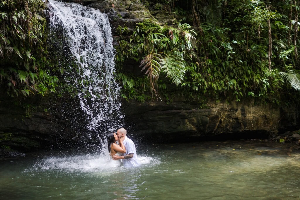 Couple standing in waterfall after rainforest elopement