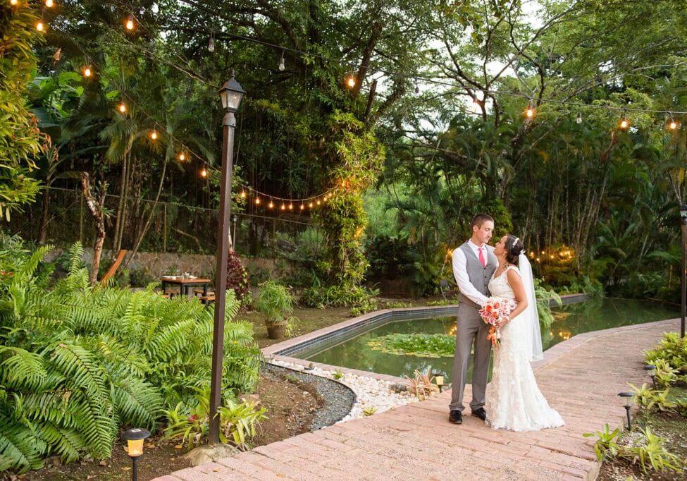 Elegant Puerto Rico wedding photographer capturing romantic couple in lush garden setting with string lights.